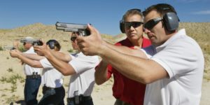 Instructor assisting officers with hand guns at firing range during weapons training